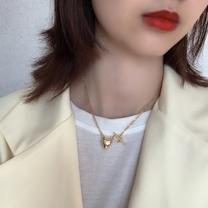 Detail of 925 silver heart necklace with toggle clasp on female model in yellow suit