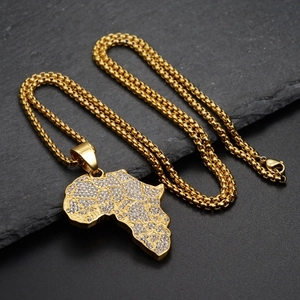 Close-up of a gold-tone iced out Africa map pendant with micro pave crystals on slate