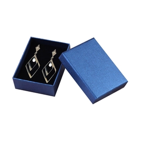 Dark blue cross-pattern jewelry gift box with golden geometric diamond earrings inside