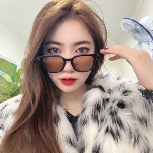Fashionable square black frame sunglasses with tea lenses worn with a faux fur coat