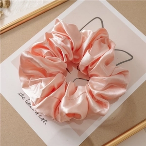 Detail of pink satin silk scrunchie with soft pearl luster and dense pleated texture