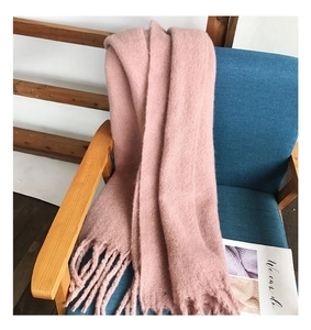 Detailed texture of pink knit cashmere-feel scarf with soft fringe on a blue chair