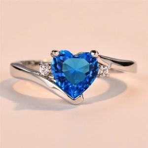 Macro shot showing blue heart-cut gemstone and cubic zirconia details on silver ring
