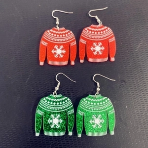 Macro detail of red and green acrylic glitter Christmas sweater earrings with snowflake pattern