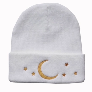 White knitted beanie with golden star and moon embroidery on the cuffed edge