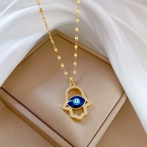 Hamsa Hand necklace with blue evil eye and sparkling crystals on beige jewelry box