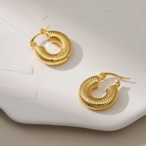 Elegant 18K gold plated brass hoop earrings with spiral texture on a ceramic tray