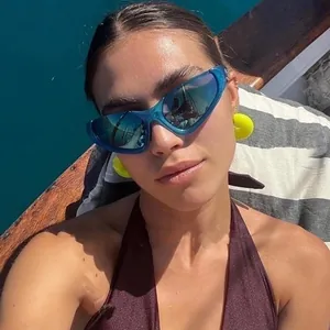 Close-up of blue translucent cat-eye sunglasses and neon yellow round earrings on model