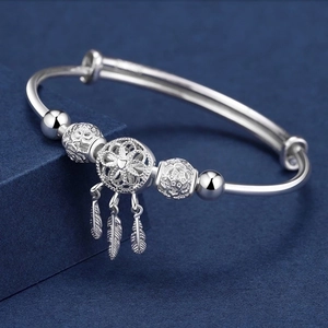 Adjustable silver dreamcatcher bangle featuring feather charms and hollow floral pendant