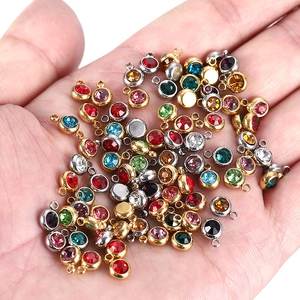 Macro shot of colorful birthstone pendants held in palm showing small size and metal base