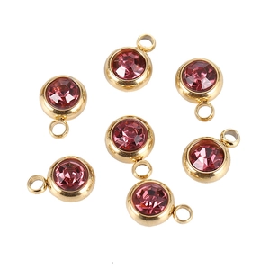 Detail of 7 golden round pendants with pinkish purple crystals for DIY jewelry making
