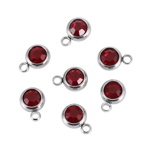 Detail of round red birthstone charms with silver-tone metal settings for DIY jewelry making