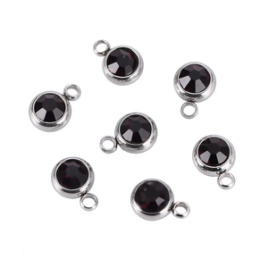 Detail of round silver birthstone charms with dark multifaceted crystals for DIY jewelry