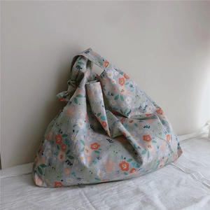 Close-up of floral cotton handbag with orange daisies on grey fabric and knotted handle