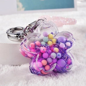Macro shot of flower-shaped acrylic keychain with moving purple glitter and macaron beads