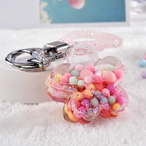 Detail of flower-shaped acrylic liquid keychain with macaron beads and pink glitter strap