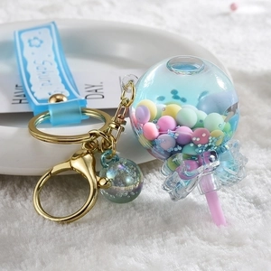 Lollipop liquid keychain with colorful beads and Sakura strap on white plush surface