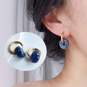 Detail of 18k gold hoop earring with a translucent dark blue textured resin pendant