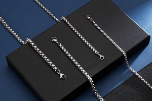 Detail view of silver stainless steel box chains with lobster clasps on blue background