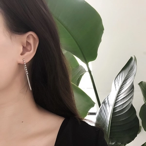Silver bead tassel chain earrings on model with tropical leaf background detail