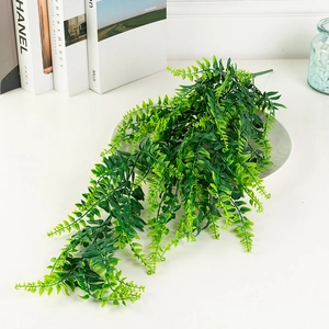 Detailed view of artificial hanging eucalyptus leaves on a white dining plate