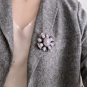 Close-up of a Baroque pearl flower brooch pinned on a grey blazer lapel