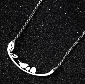 Macro shot of silver bird and leaf silhouette pendant on a delicate metal chain