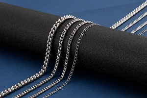 Detail view of various stainless steel chain necklaces with metallic texture on black display