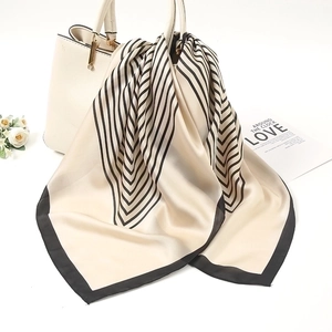 Detail of silk-feel cashew print scarf elegantly draped over a white fashion handbag