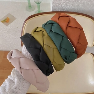 Detail of five multi-colored braided headbands in silk texture on a white knit fabric