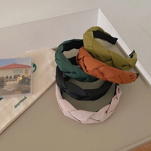 Detail of five braided fabric headbands in green, caramel, black and pink colors