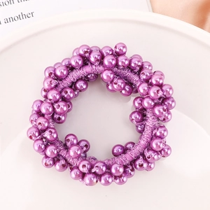 Close-up of a purple pearl hair tie on a white porcelain plate with a clean background