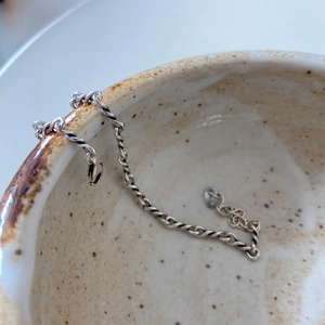 Macro shot of handcrafted 925 sterling silver twisted chain bracelet on a ceramic edge