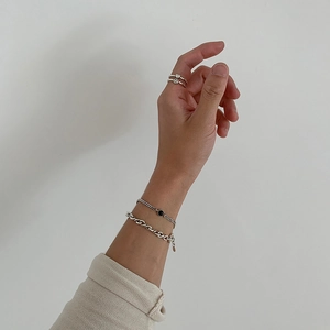Close-up of 925 sterling silver handmade twisted bracelet and rings with heart smiley charms