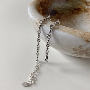 Macro detail of 925 sterling silver twisted rope chain with extension links on ceramic bowl
