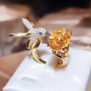 Exquisite gold hummingbird ring with oval yellow gemstone and white zircon accents