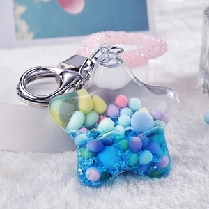 Star-shaped liquid shaker keychain with colorful beads and blue glitter on white fur