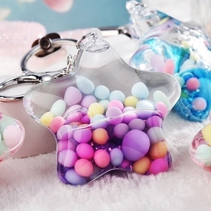 Quicksand star acrylic keychain with colorful beads and glitter on soft plush surface