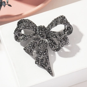 Detail of vintage bow brooch with black rhinestones and intricate cut-out patterns
