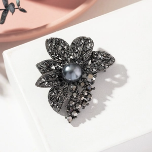 Macro shot of vintage dark grey crystal flower brooch with a central large black pearl