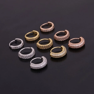 Macro shot of circular cartilage earrings in gold, silver, and rose gold with pavé zircon