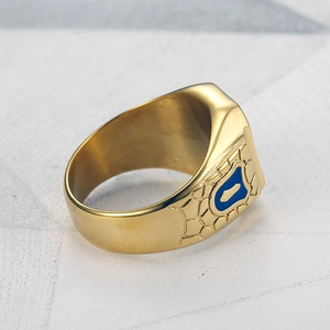 Macro shot of men's gold plated stainless steel ring with blue enamel shield and grid carving