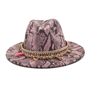 Détail d'un fedora rose avec imprimé serpent, ruban tressé ethnique et breloques coquillages
