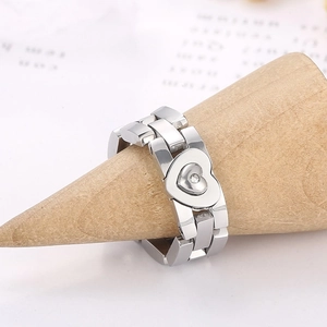 Macro shot of silver stainless steel heart ring on wooden display stand with sleek chain link