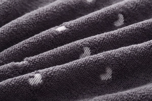 Macro shot of gray cotton towel with white heart jacquard pattern and thick loops