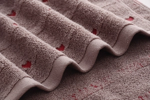 Detail of soft jacquard cotton towel with red heart patterns and dense terry loops