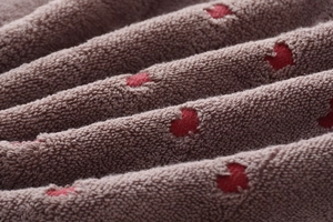 Close-up of soft thick cotton towel with red heart jacquard pattern and plush loops