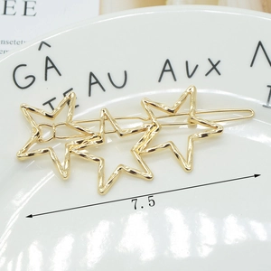 Detailed view of 7.5cm gold hollow star hair clip with hammer texture on ceramic plate