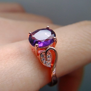 Detail of rose gold ring with large oval purple gemstone and leaf-shaped diamond accents