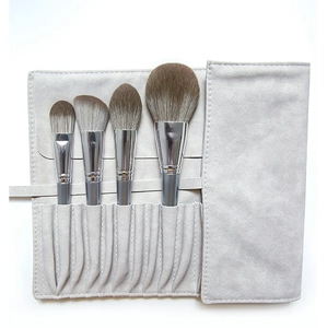 Detail of 4 makeup brushes with grey handles and a matching faux suede roll-up storage bag